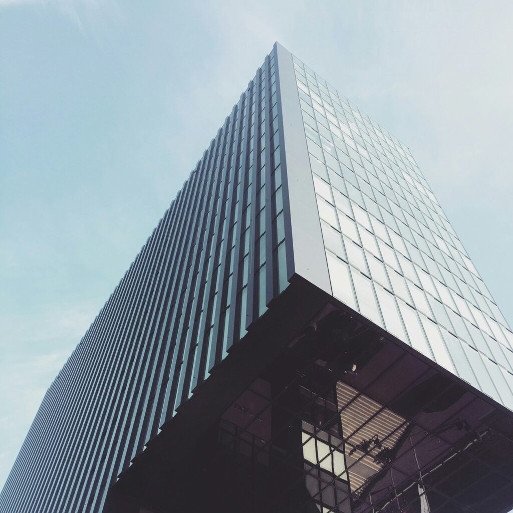 Capital improvements by Reliant Construction: A modern office building under renovation with red scaffolding, skilled workers, and premium construction materials. Upgrade your commercial space today with expert craftsmanship—contact us now!
